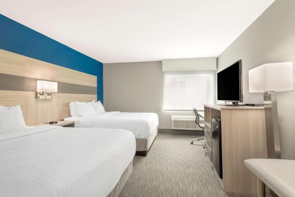 a hotel room with two beds and a flat screen tv at Best Western Plus Magnolia Inn & Suites in Cleveland