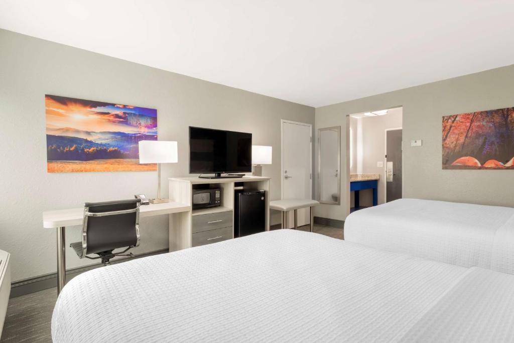 a hotel room with two beds and a desk and a tv at Best Western Plus Magnolia Inn & Suites in Cleveland