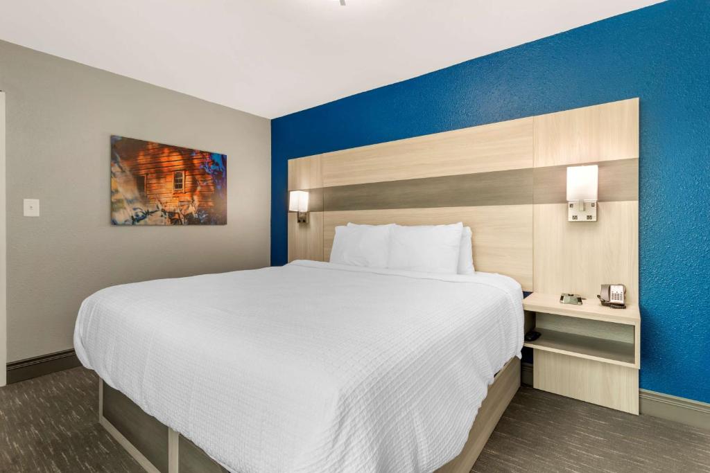 a large white bed in a room with a blue wall at Best Western Plus Magnolia Inn & Suites in Cleveland