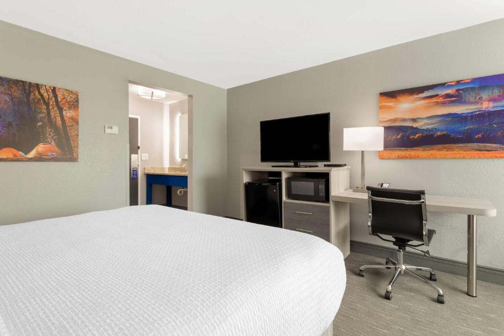 a hotel room with a bed and a desk and a tv at Best Western Plus Magnolia Inn & Suites in Cleveland