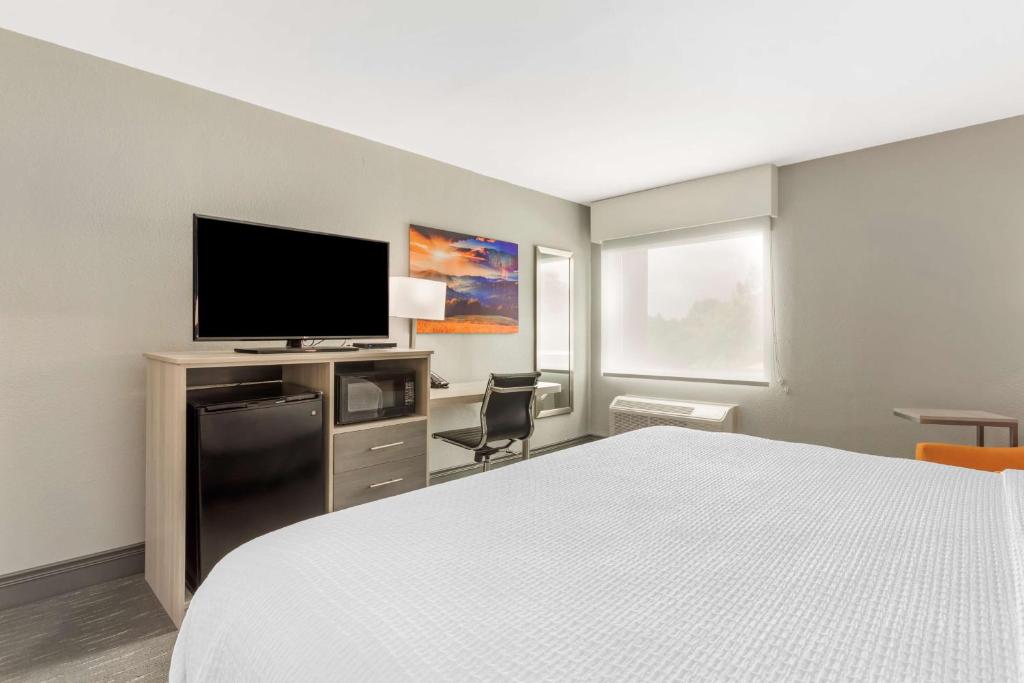 a hotel room with a bed and a flat screen tv at Best Western Plus Magnolia Inn & Suites in Cleveland