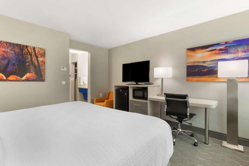 a hotel room with a bed and a desk and a television at Best Western Plus Magnolia Inn & Suites in Cleveland