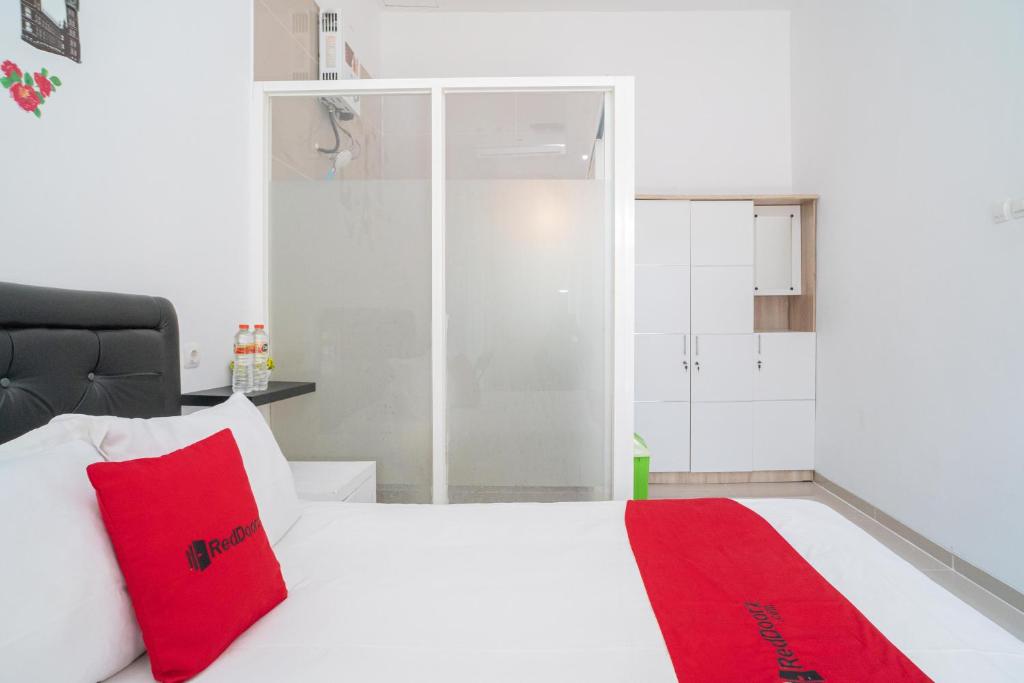 1 dormitorio con cama blanca y almohadas rojas en RedDoorz Syariah At Winong Nganjuk, en Nganjuk