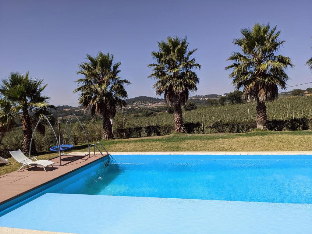 a blue swimming pool with palm trees in the background at Entre Pomares in Alcobaça