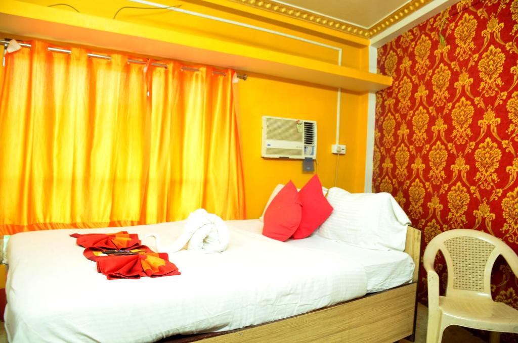 um quarto com uma cama com cortinas vermelhas e amarelas em STAYMAKER Royal Residency em Calcutá