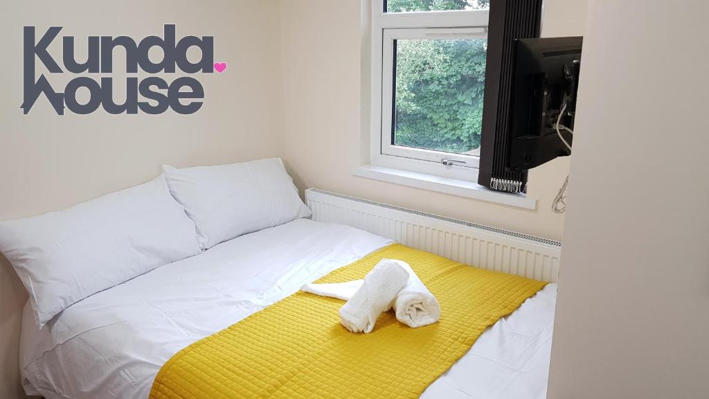 Una cama blanca con una toalla sobre una manta amarilla en Kunda House Bournbrook en Birmingham