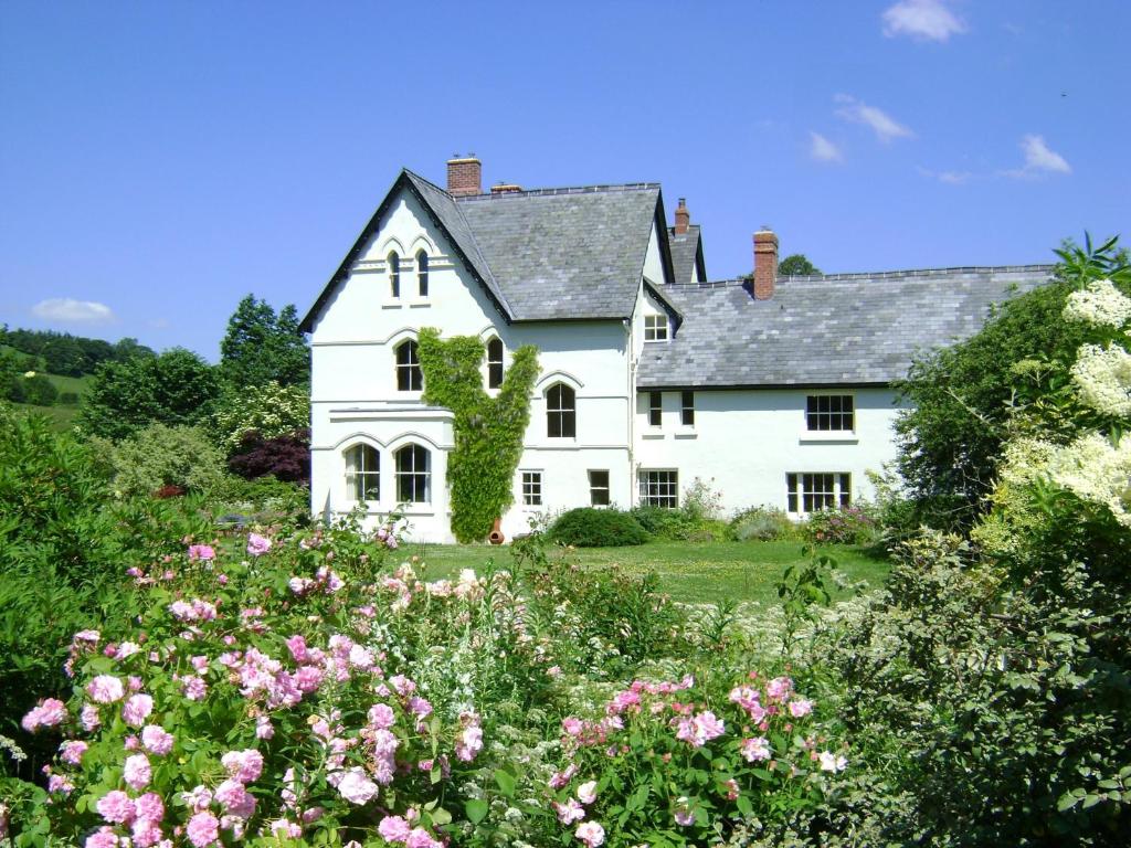a white house with flowers in front of it at The Forest Country House B&B in Newtown