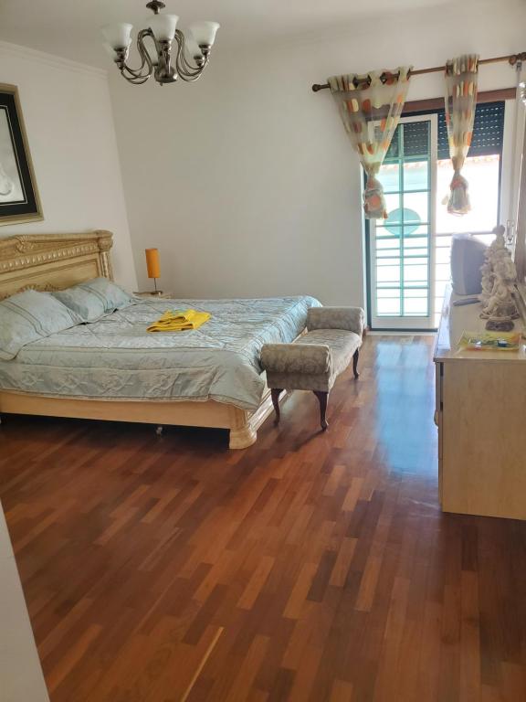 sypialnia z łóżkiem i drewnianą podłogą w obiekcie Alojamento Bertil w mieście Nazaré