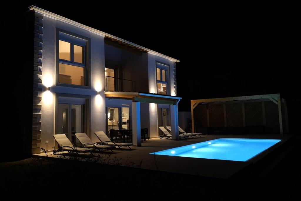 a house with a swimming pool at night at Sunset Sea View Villa 8 in Afionas