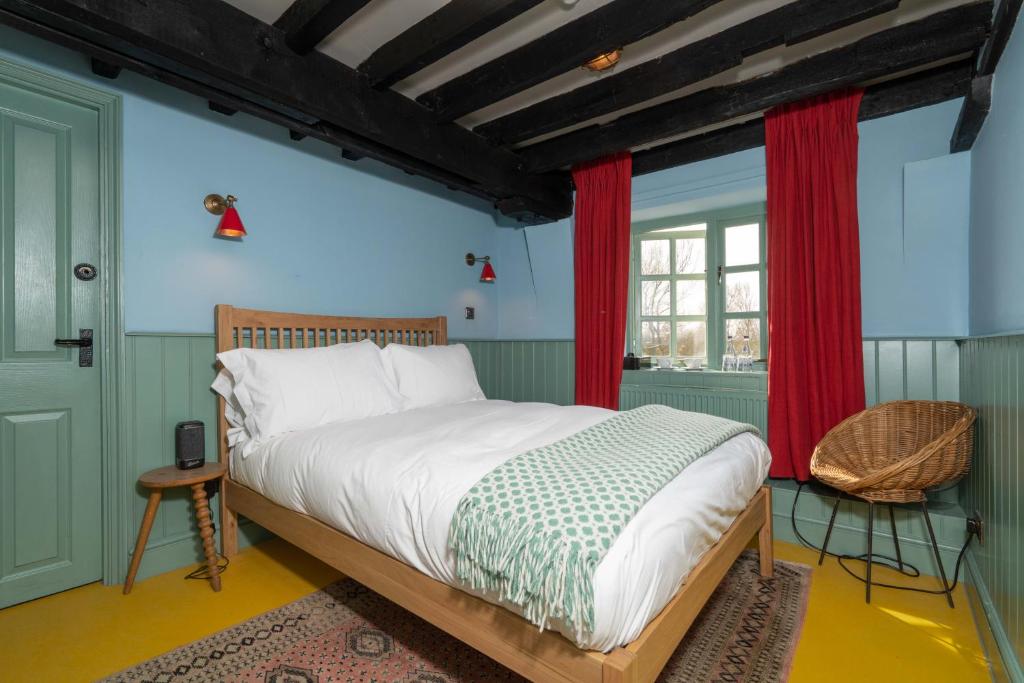 a bedroom with a bed and red curtains at Sculthorpe Mill in Fakenham