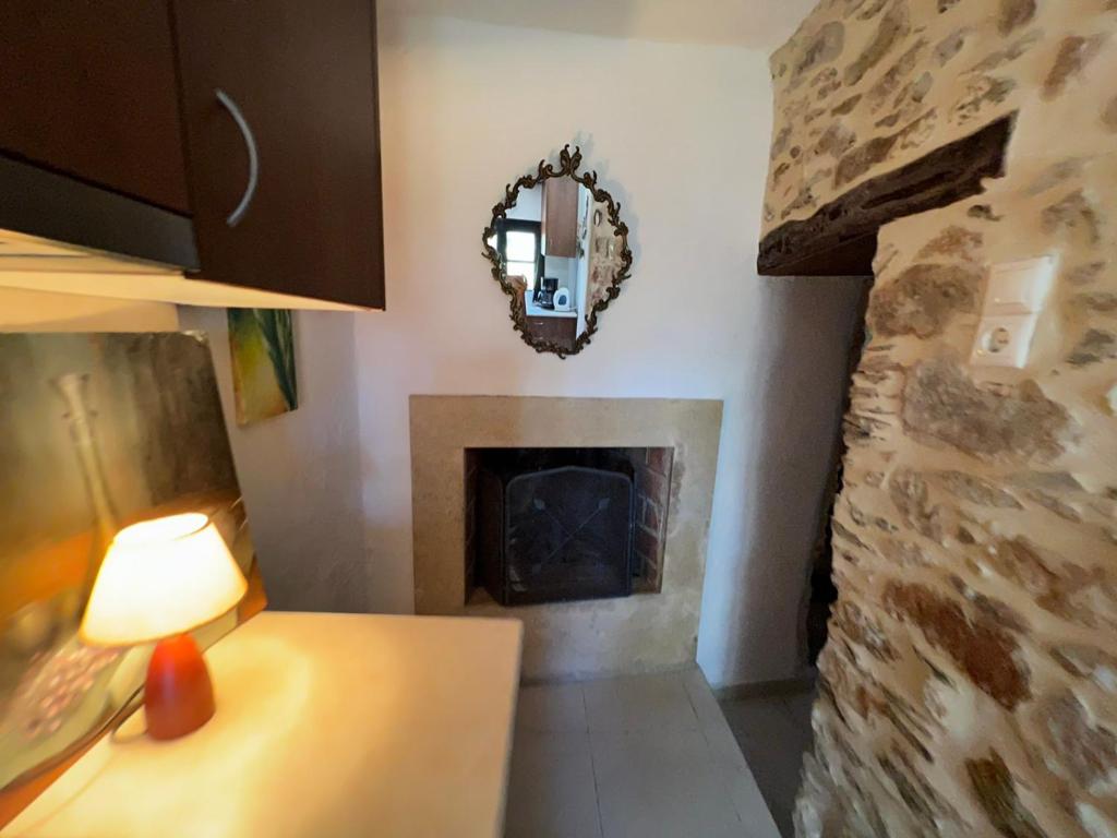 ein Wohnzimmer mit einem Kamin und einem Spiegel in der Unterkunft Πετροχτιστο Αρχοντικό με υπεροχή θεα in Rodhiá