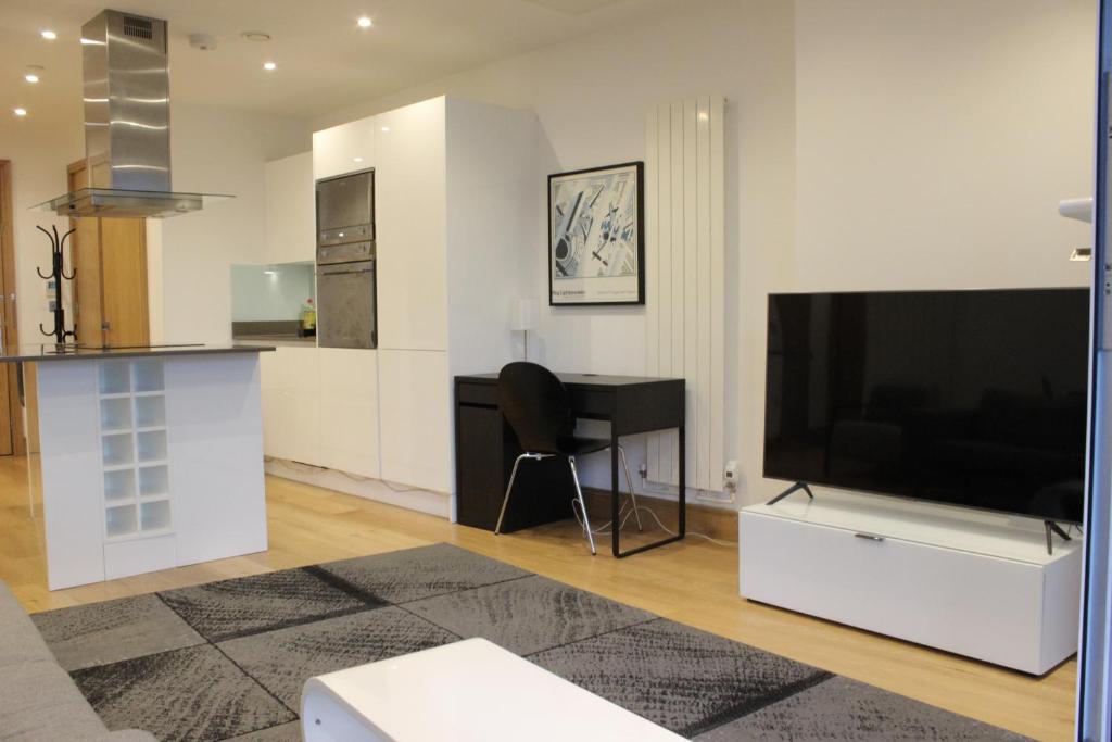 a living room with a large television and a desk at Luxury Canary Wharf 2 Bed Apartment With Panoramic Views in London