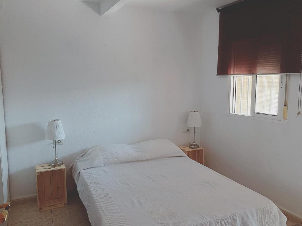 1 dormitorio con 1 cama blanca y 2 lámparas en Apartamentos MásBambú, en Málaga
