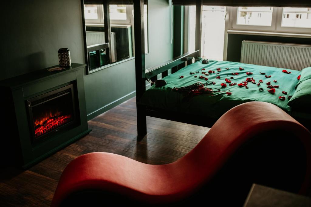 トルンにあるMake Love Apartment Premiumのベッドルーム1室(ベッド1台、暖炉、赤い椅子付)