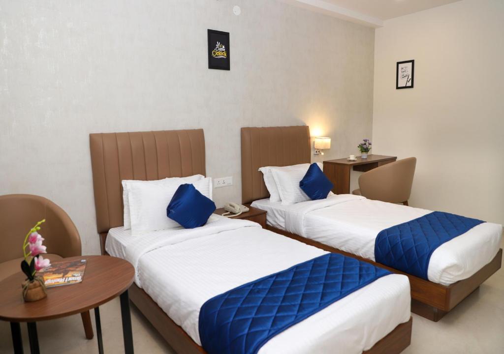 a hotel room with two beds and a table at Admira Residency in Coimbatore