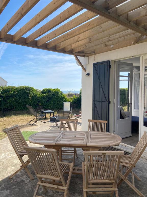 Une table et des chaises en bois sont disponibles sur la terrasse. dans l'établissement Maison de vacances en bordure de mer !, à Batz-sur-Mer