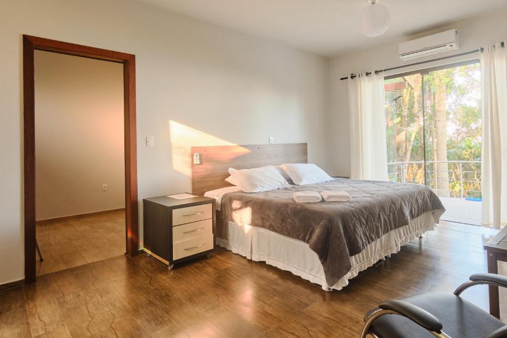 um quarto com uma cama e uma grande janela em Sertão House - Fantástica residência em meio a natureza intocada no sul da ilha em Florianópolis