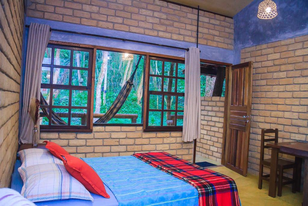 ein Schlafzimmer mit einem Bett in einem Zimmer mit Fenstern in der Unterkunft Chalé 03 Itaipu Vale da Colina Niterói in Niterói