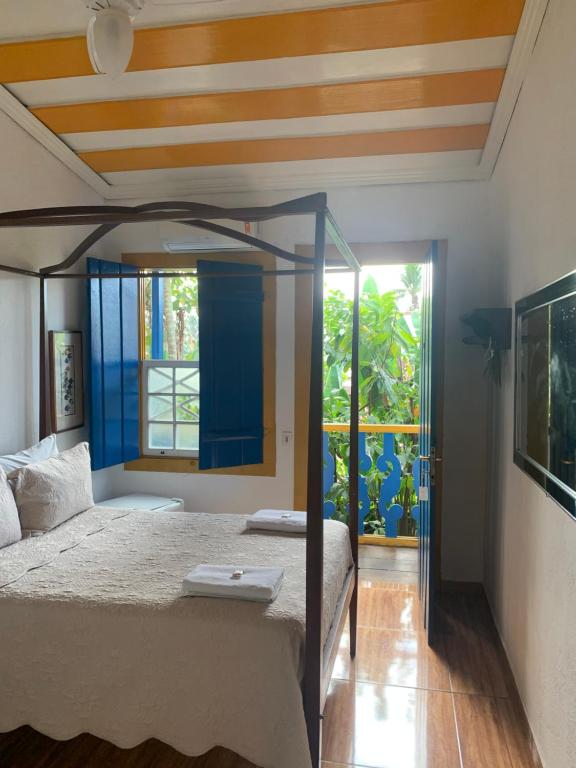 ein Schlafzimmer mit einem Himmelbett und einem Fenster in der Unterkunft Suítes Casa da Colônia in Paraty