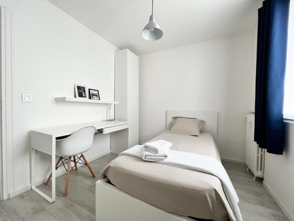 a small white bedroom with a bed and a desk at Une pause à Evreux logement entier in Évreux