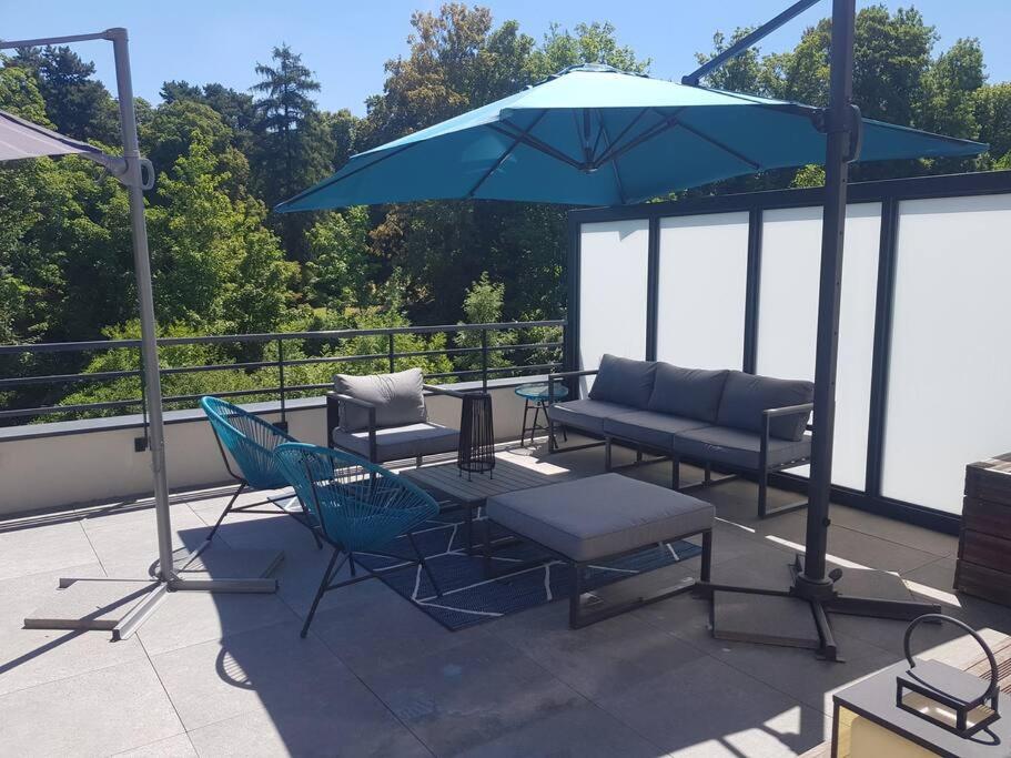un patio con 2 sillas y una sombrilla azul en Appartement d'exception - Vue panoramique sur lac, en Évian-les-Bains