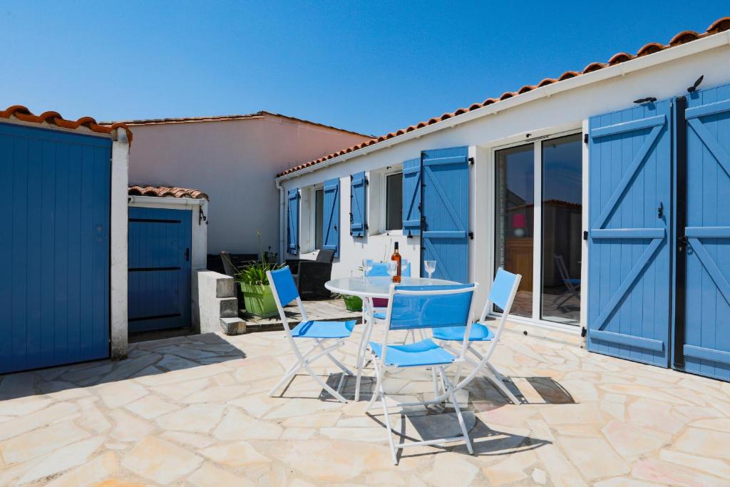 d'une terrasse avec des portes bleues, une table et des chaises. dans l'établissement Maison confortable à deux pas du village, à La Flotte