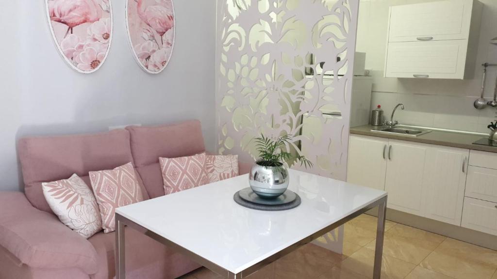 un salon avec une table blanche et un canapé rose dans l'établissement Apartamento Los Padrinos, à Cordoue