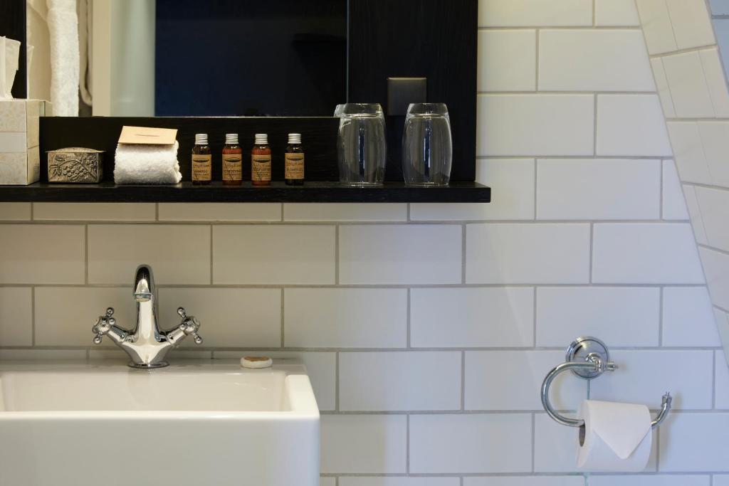 a white bathroom with a sink and a mirror at First Hotel Grand in Odense