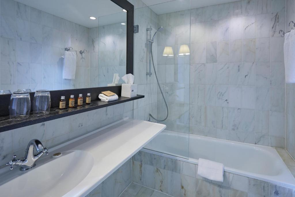 a bathroom with a tub and a shower and a sink at First Hotel Grand in Odense
