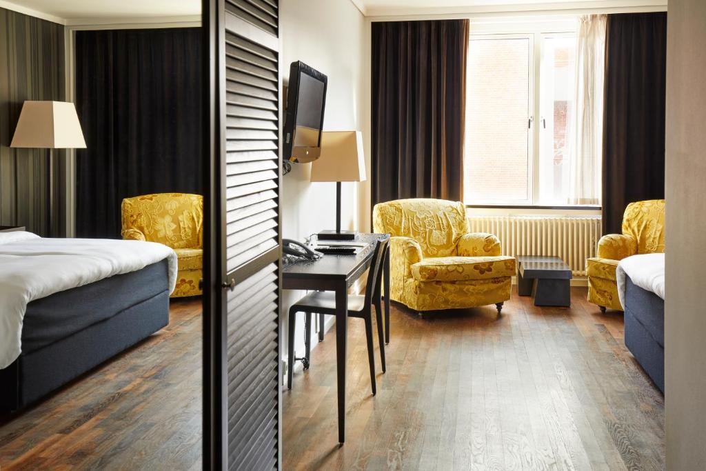 a hotel room with a bed and a desk and chairs at First Hotel Grand in Odense