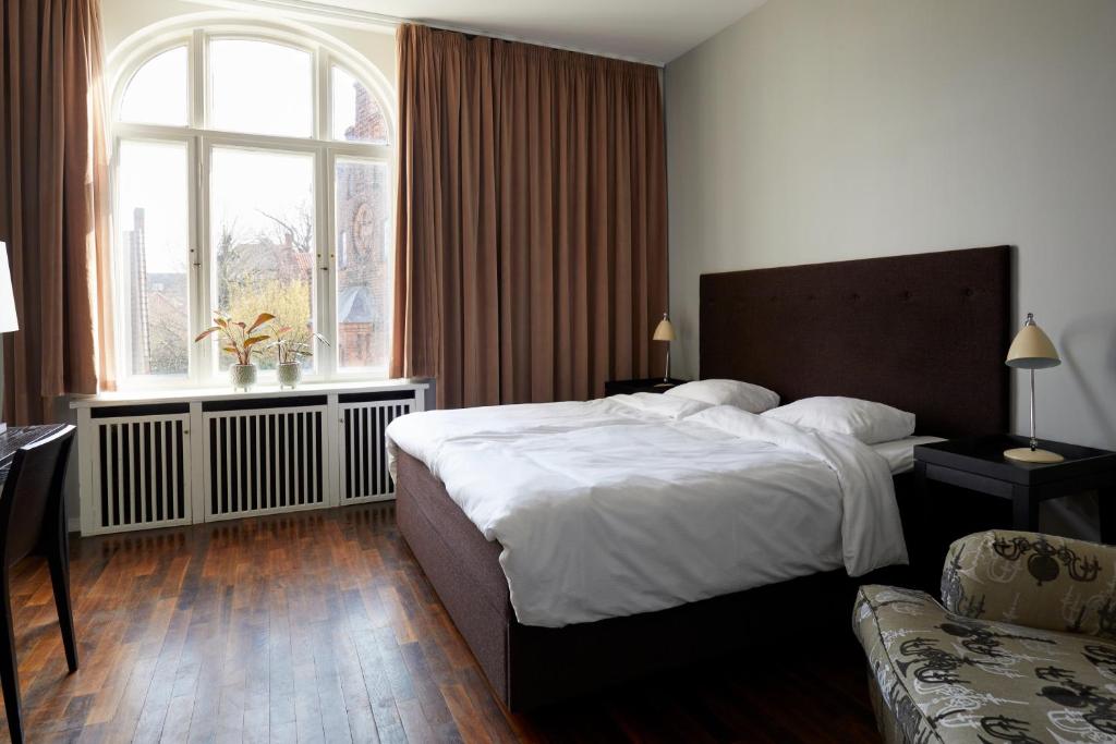 a bedroom with a large bed and a window at First Hotel Grand in Odense