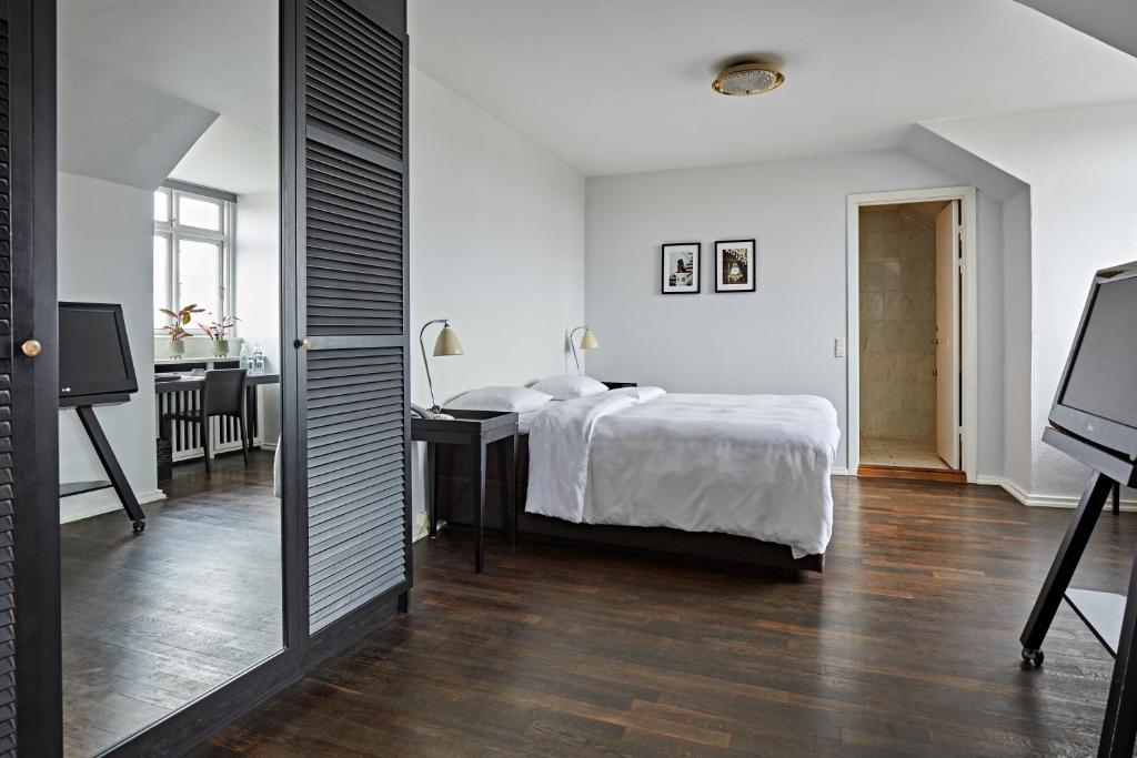 a bedroom with a bed and a desk and a television at First Hotel Grand in Odense