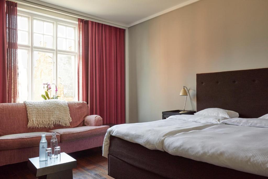 a bedroom with a bed and a couch and a window at First Hotel Grand in Odense
