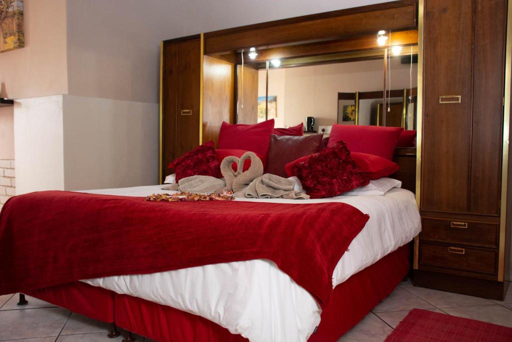 1 dormitorio con 1 cama grande con almohadas rojas en Namaqua Lodge, en Vanrhynsdorp