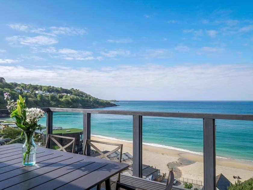 a vase of flowers sitting on a wooden table on the beach at Glas Mordros in St Ives
