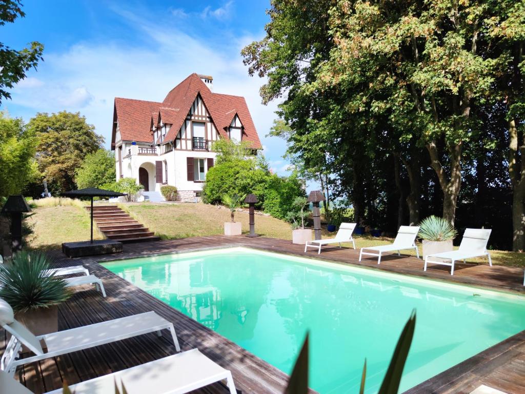 a house with a swimming pool in front of a house at Villa avec vue et piscine à moins d'1h de Paris in Rolleboise