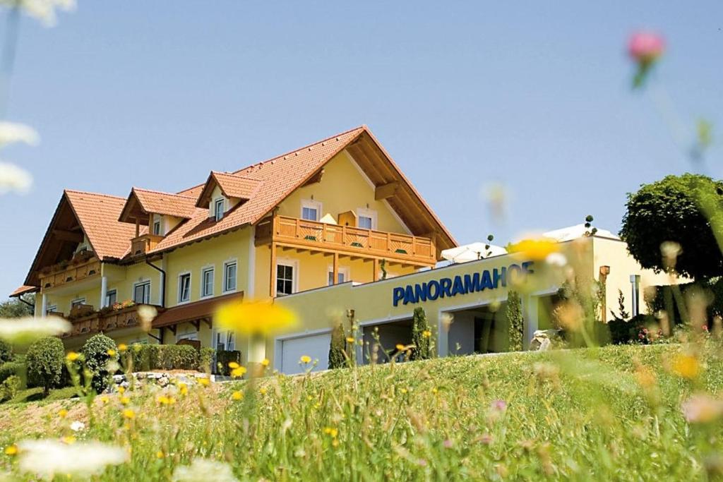 ein Haus auf einem Hügel neben einem Blumenfeld in der Unterkunft Hotel Panoramahof Loipersdorf in Jennersdorf