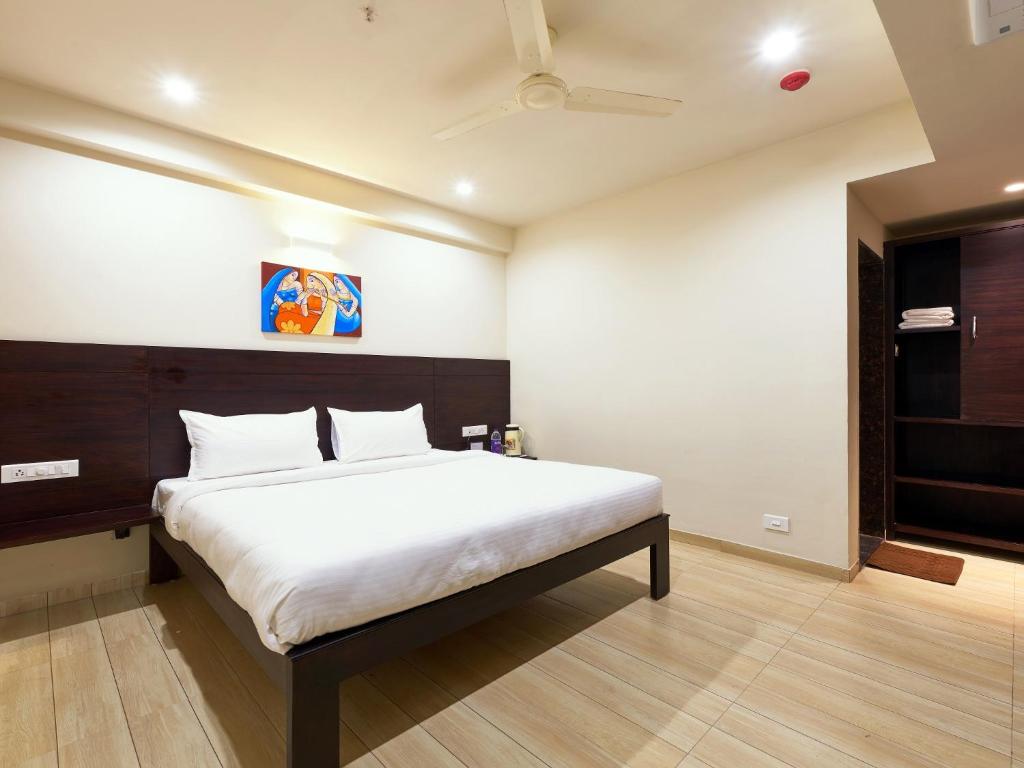 a bedroom with a large white bed with a ceiling at Hotel Tulsi-100 Feet From Ambabai Temple, Kolhapur in Kolhapur