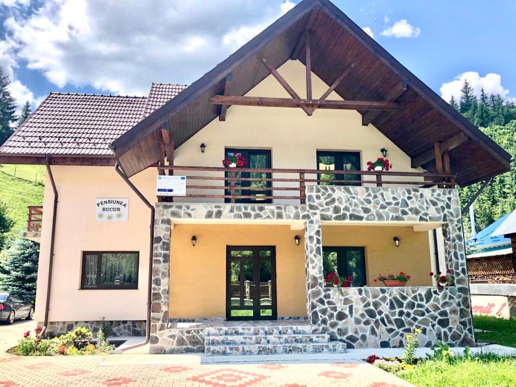 a house with a balcony on top of it at Pensiunea Bucur in Dămuc
