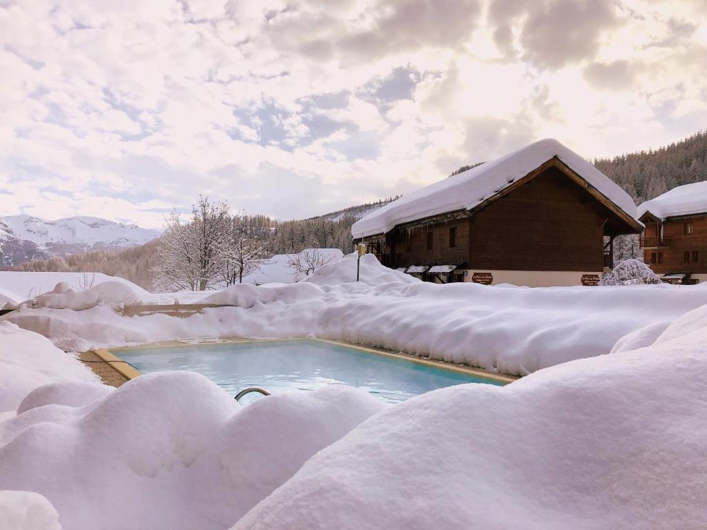 ピュイ・サン・ヴァンサンにあるLes Chalets du Parc aux Etoiles - Cimes et Neigeの雪に覆われた家の隣のスイミングプール