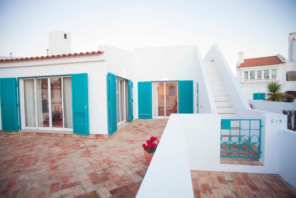 a white house with blue doors and a staircase at Cozy summer house in Alvor
