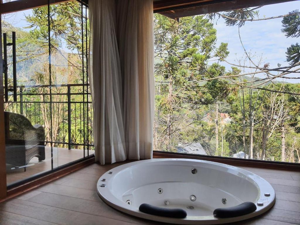 a bath tub in a room with a large window at POUSADA GRESSONEY MOUNTAIN in Monte Verde