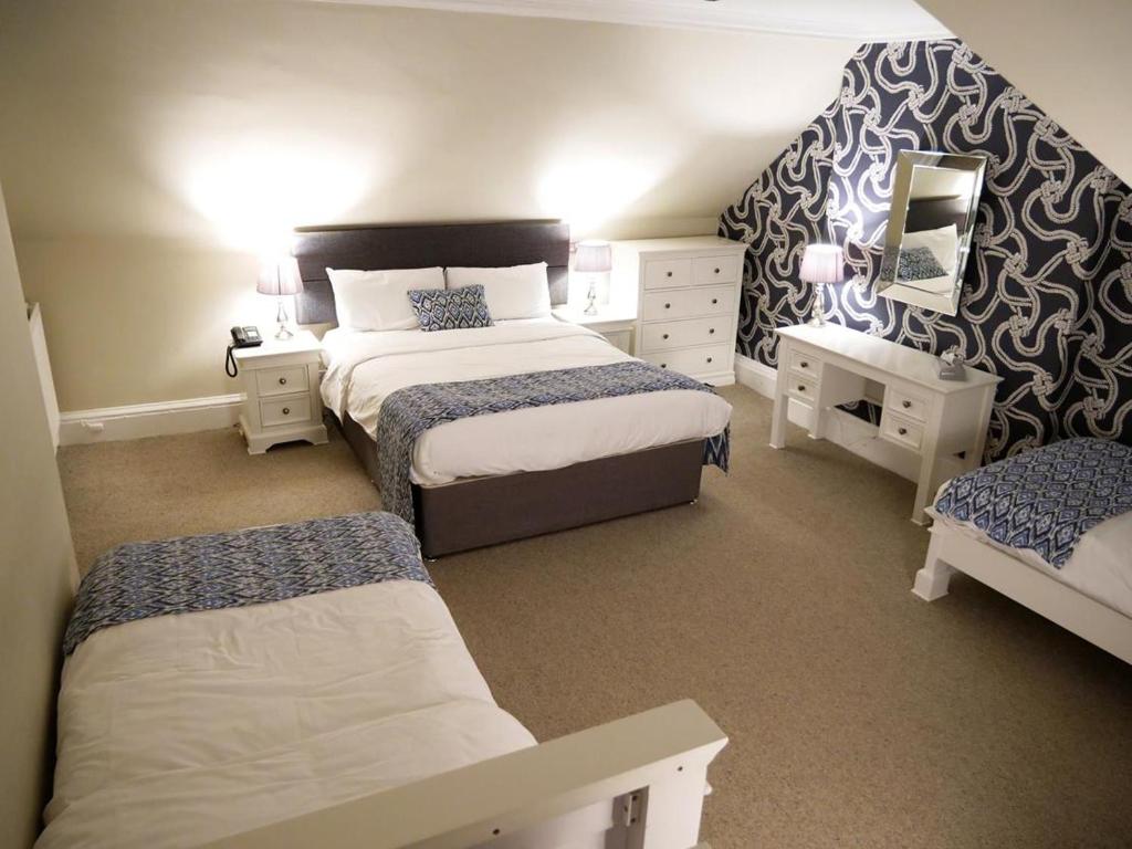 a small bedroom with two beds and a mirror at The Victoria Hotel in Bamburgh