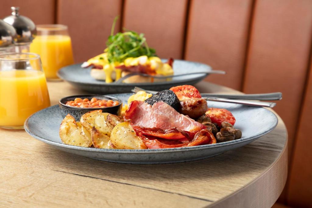 two plates of food on a table with orange juice at The Victoria Hotel in Bamburgh