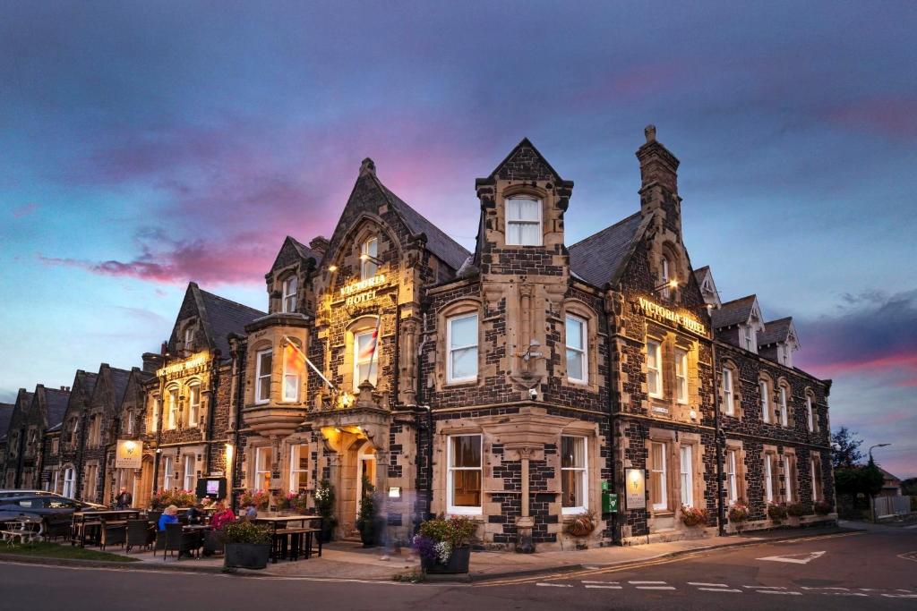 un gran edificio de piedra con luces. en The Victoria Hotel, en Bamburgh