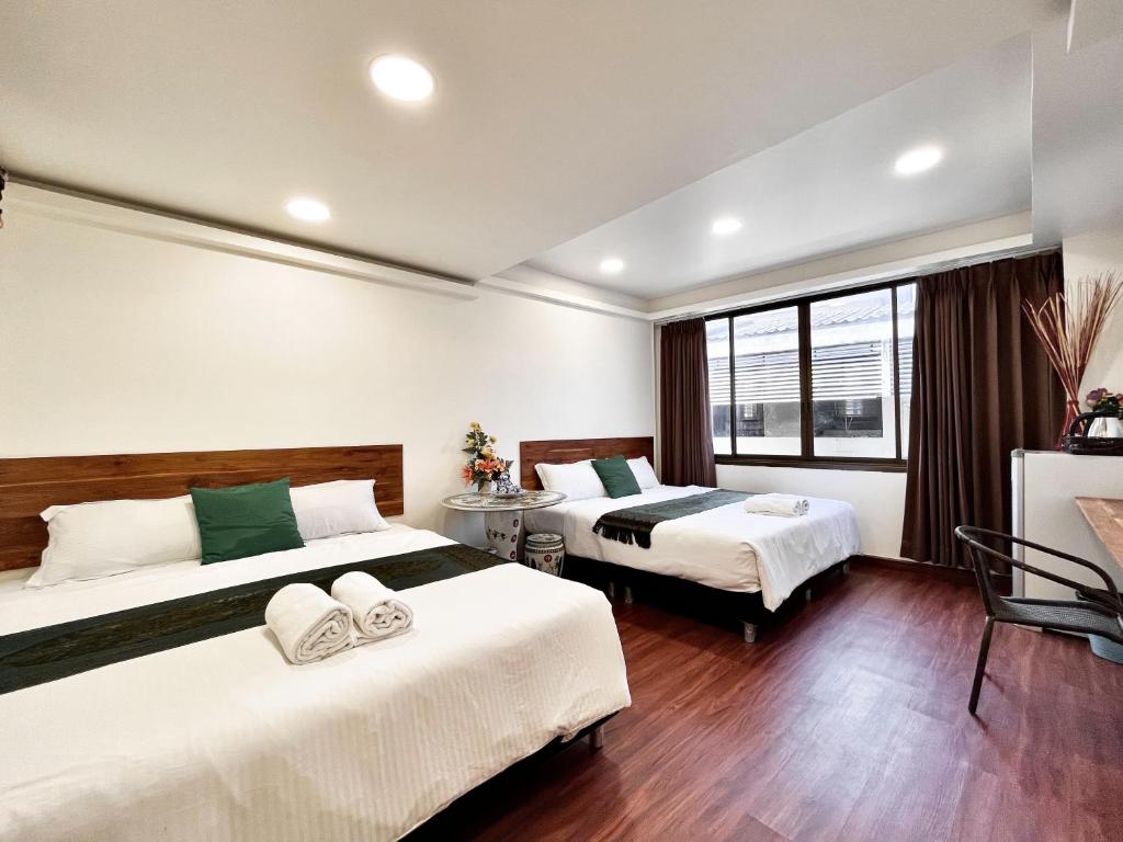 een hotelkamer met 2 bedden en een raam bij Longzhu Guesthouse in Bangkok