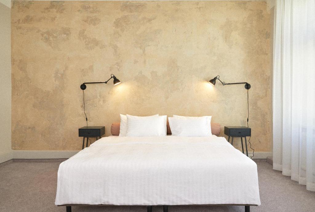 維也納的住宿－Hotel Babula am Augarten，一间卧室配有一张带两盏灯的大型白色床。