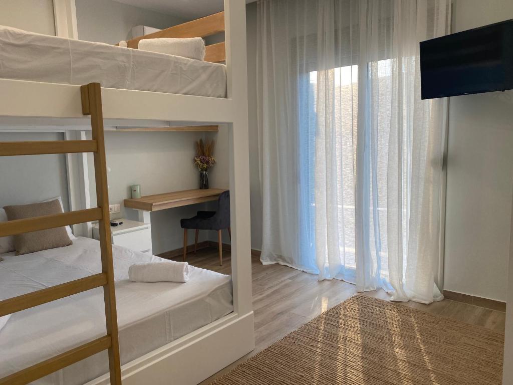 sypialnia z łóżkiem piętrowym, biurkiem i oknem w obiekcie Villa Massari w mieście Charaki