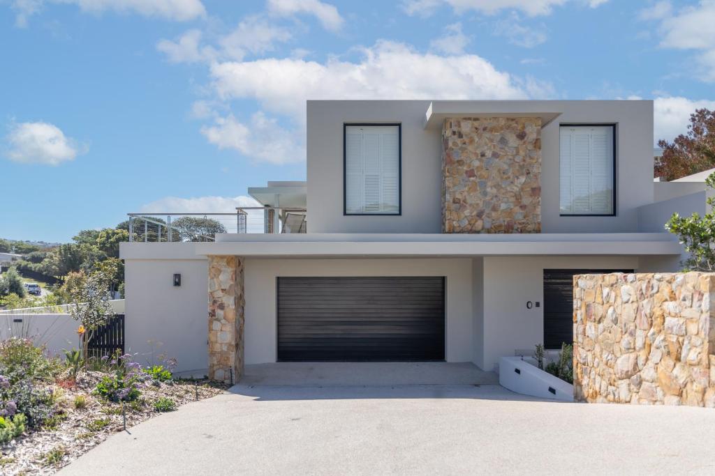 uma casa branca com garagem em Sunset Villa - brand new home 200m from the beach em Plettenberg Bay