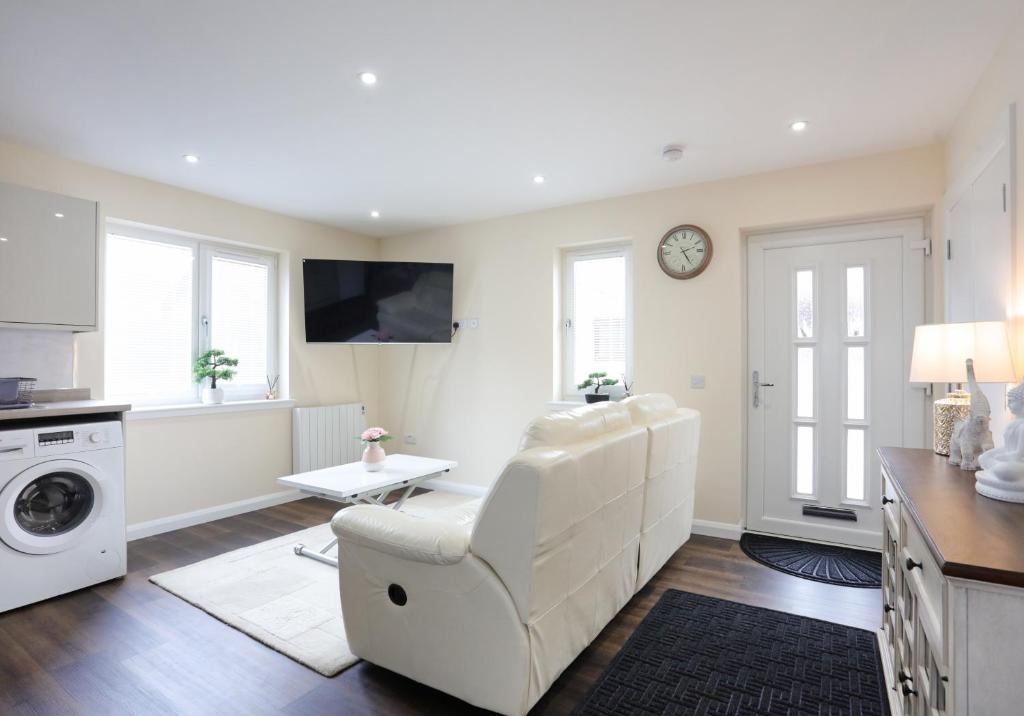 a white living room with a white chair and a table at Canal View Cottage 